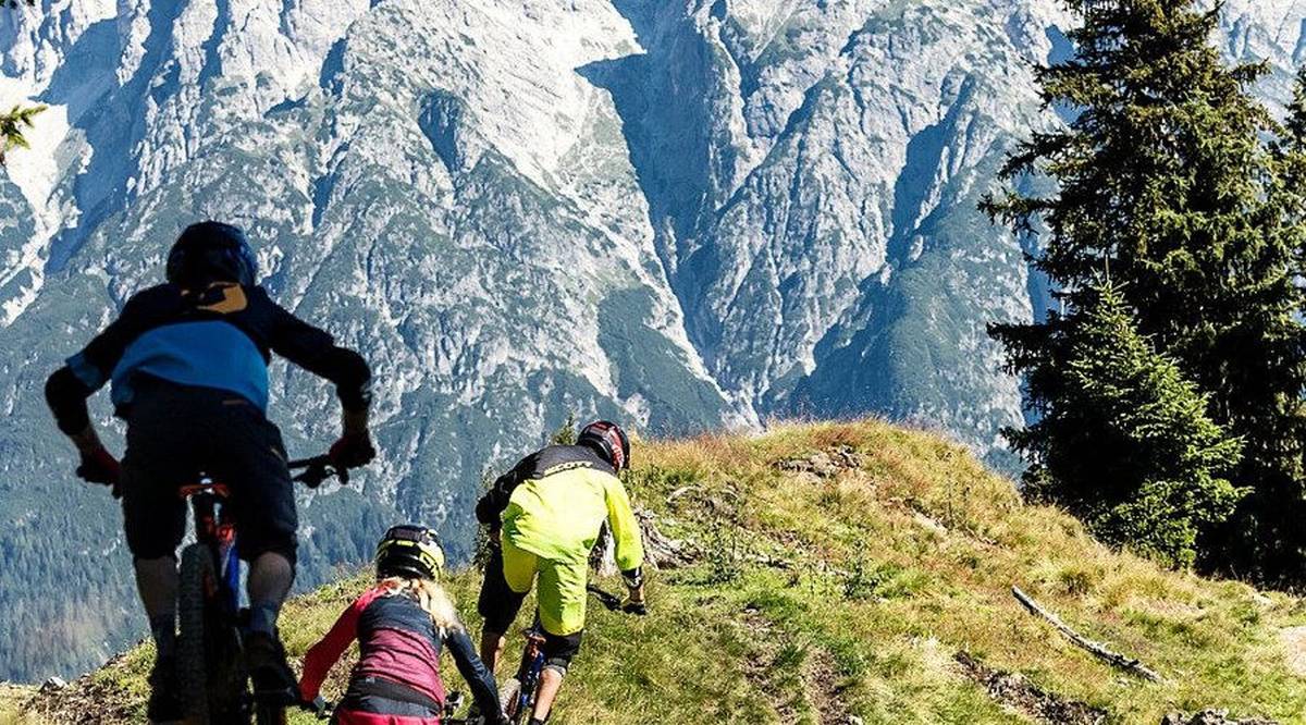 Biker am Hang über Leogang mit Kalkalpen im Hintergrund